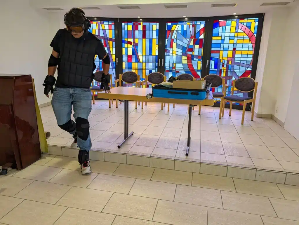 Ein Schüler trägt den Alterssimulationsanzug GERT und erlebt mit Gewichten, Bewegungseinschränkungen und einer Simulationsbrille körperliche Einschränkungen im Alter.