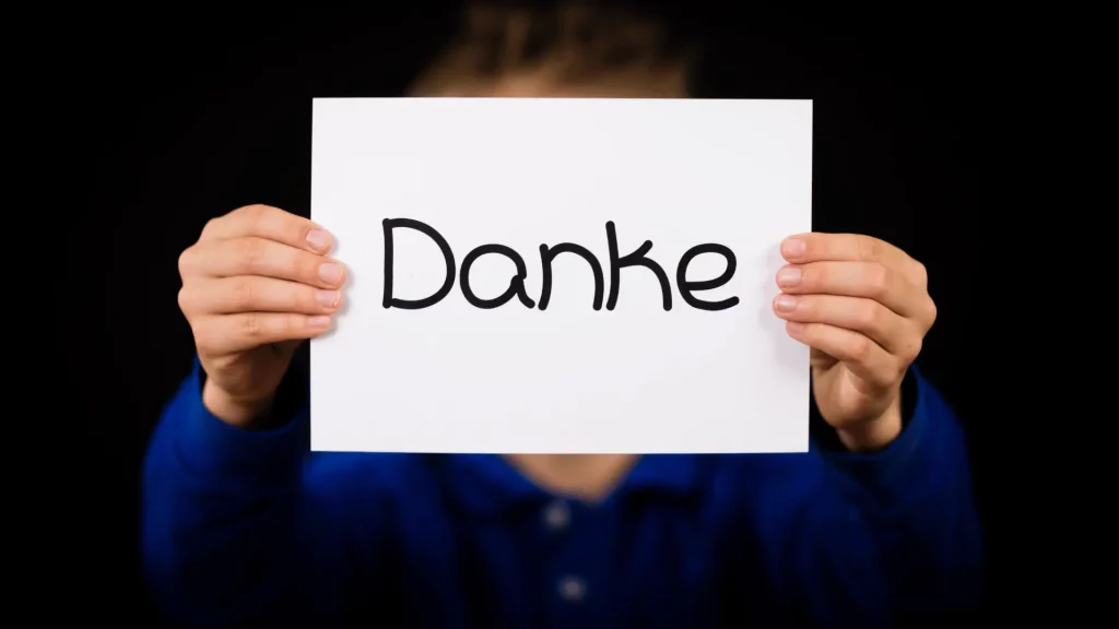Zwei Hände halten einen Zettel auf dem Danke geschrieben steht.