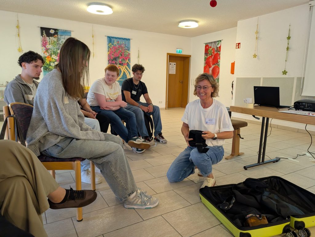 Eine Mitarbeiterin des Haus Ruhrgarten erklärt Schüler:innen die Bestandteile des Alterssimulationsanzugs GERT und zeigt, wie körperliche Einschränkungen im Alter nachempfunden werden können.
