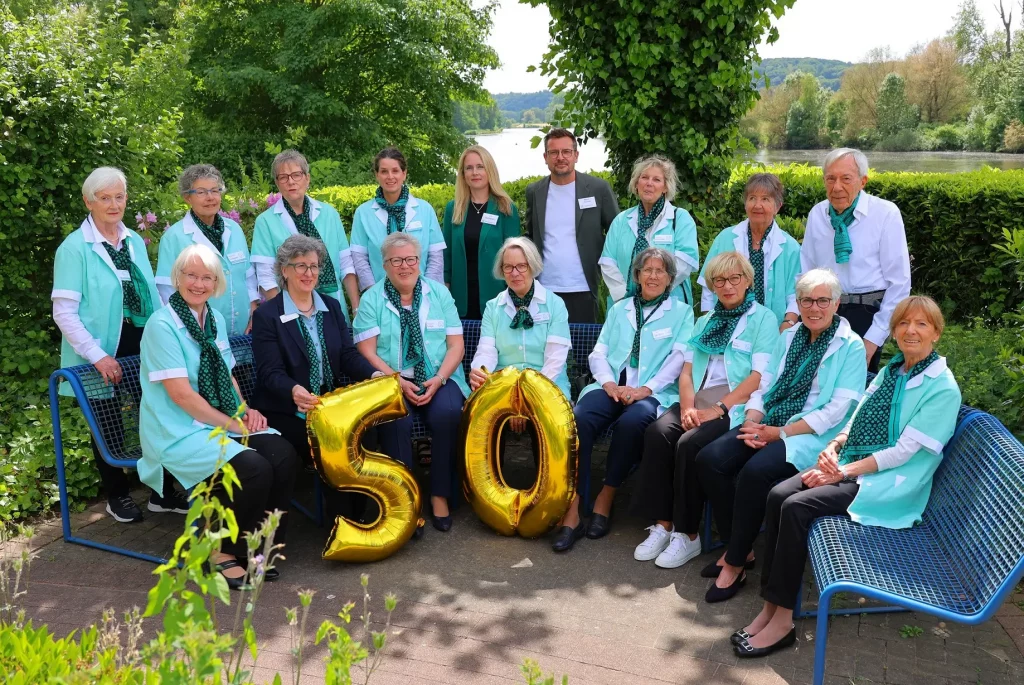 Gruppenfoto der Grünen Damen und Herren sowie Alise Höhn, Nina Eumann und Marco Warnath mit goldener Ballon-Fünfzig im Garten an der Ruhr.
