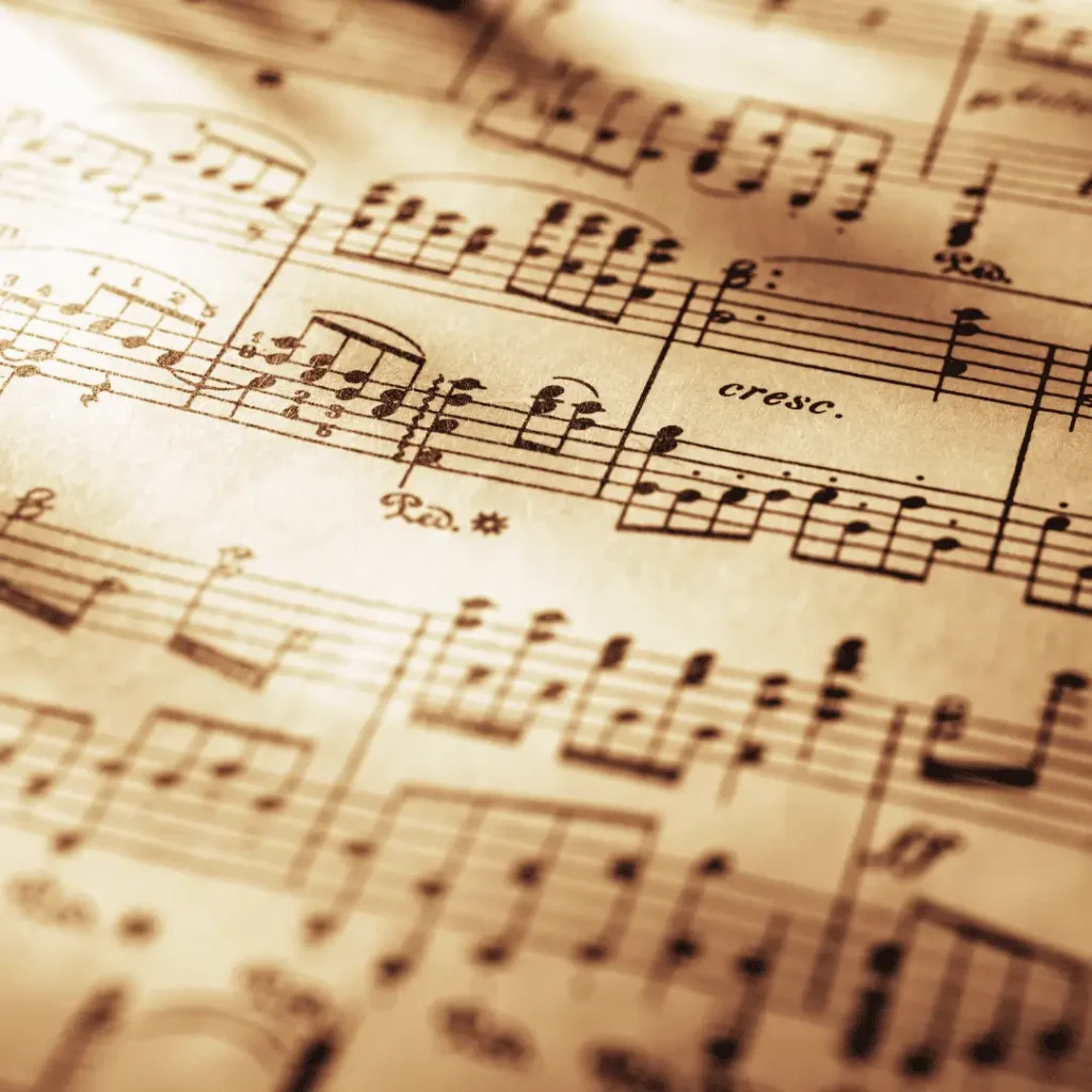 Nahaufnahme von handgeschriebenen Noten auf vergilbtem Notenpapier. Mehrere Notenzeilen und musikalische Zeichen sind deutlich zu erkennen.