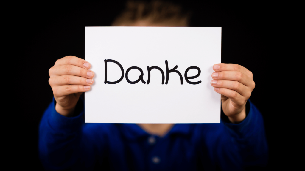 Zwei Hände halten einen Zettel auf dem Danke geschrieben steht.