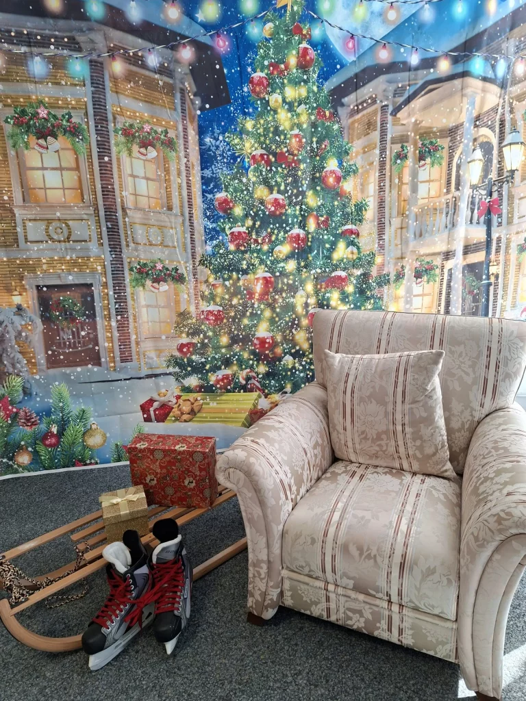 Sessel, daneben ein Schlitten mit Schlittschuhen und weihnachtlichem Hintergrund